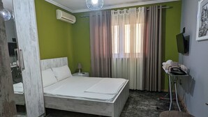 Un dormitorio con cama, aire acondicionado, televisor y espejo.