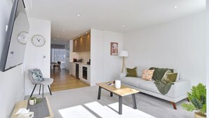 Een moderne woonkamer met een bank, salontafel en een televisie aan de muur.