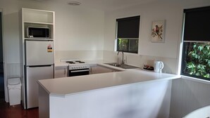 Eine kompakte Küche mit Kühlschrank, Herd, Mikrowelle und Spüle.