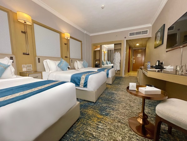 Habitación de hotel con dos camas, un escritorio, una silla, una mesita y un baño visible a través de una puerta abierta.