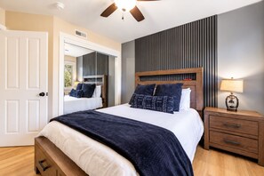 A bedroom with a bed, bedside table, lamp, and a window with blinds.
