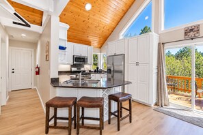 Une cuisine moderne avec des armoires blanches, des appareils en acier inoxydable et un plafond en bois.