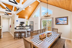 A spacious kitchen with white cabinets, a central island, and a dining area with a checkered tablecloth.