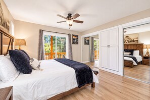 Une chambre à coucher comprenant un lit, un ventilateur de plafond, une table de chevet, une lampe et une vue sur une terrasse extérieure.