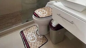 Een badkamer met douche, toilet en wastafel.