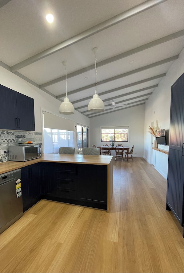 Una cocina moderna con una isla central, piso de madera e iluminación colgante.