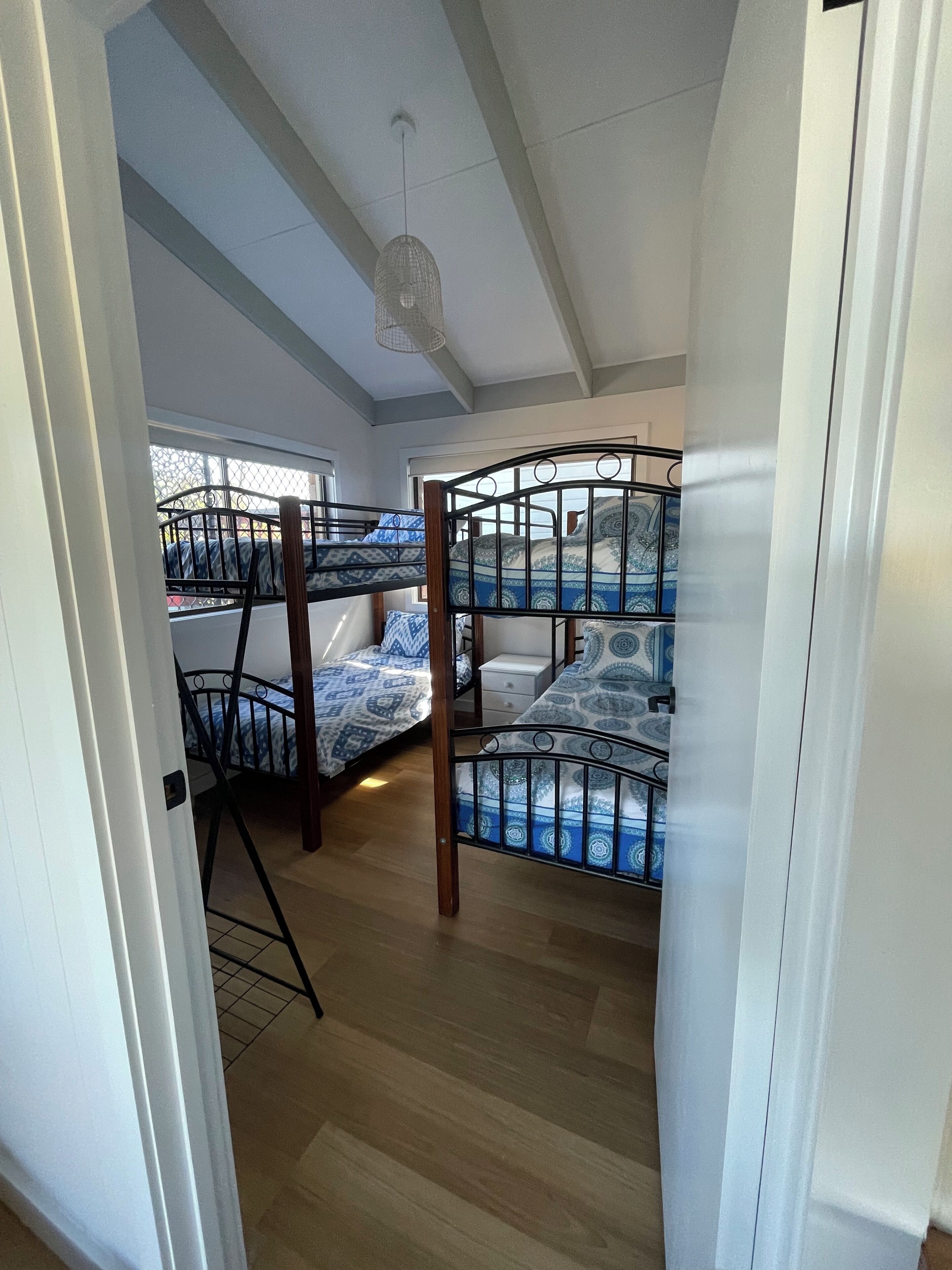 Una habitación con literas, una lámpara colgante y una ventana con vistas.