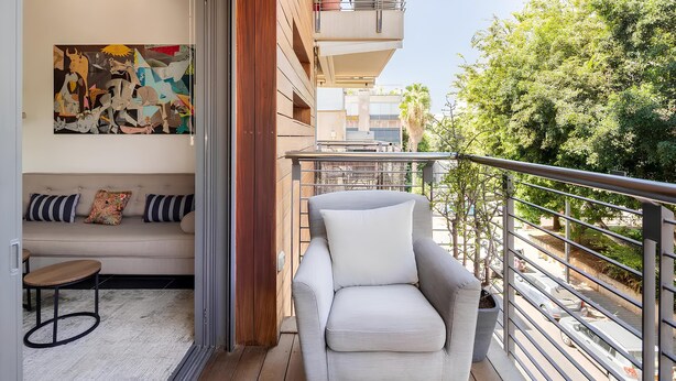 A balcony with a grey armchair, a sofa with patterned cushions, and a wooden floor. - Luxury Oasis Tel Aviv Beach

2BD Apt & Parking 2 minute walk from the beach (Tel Aviv-Yafo)