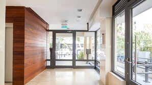 A modern hotel lobby with a wooden accent wall, a glass door entrance, and a view of the street outside. - Luxury Oasis Tel Aviv Beach

2BD Apt & Parking 2 minute walk from the beach (Tel Aviv-Yafo)