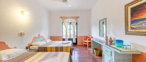 A hotel room with two beds, a desk, a chair, a ceiling fan, and a painting on the wall.