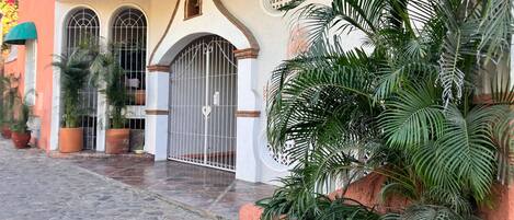 A building with a gated entrance, potted plants, and a cobblestone pathway.