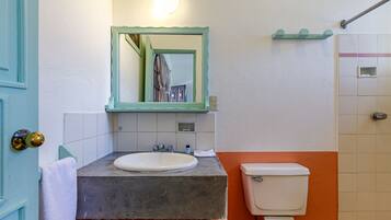 Un baño con lavamanos blanco, inodoro y zona de ducha.