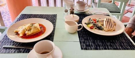 Ett bord dukat med en tallrik ravioli, en kopp kaffe och en tallrik med grönsaker.