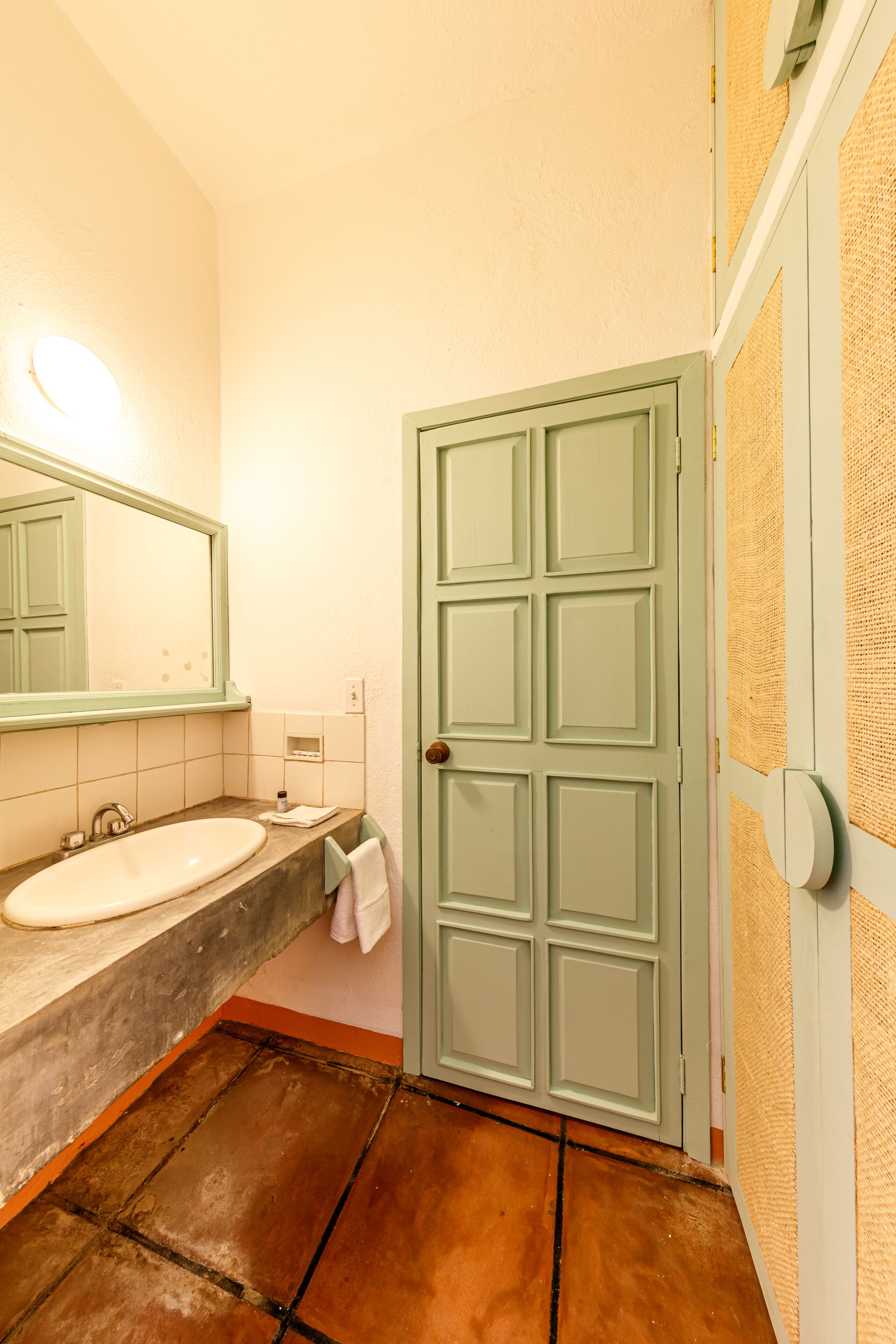 A bathroom with a sink, mirror, and a door with a textured wall.