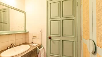 A bathroom with a sink, mirror, and a door with a textured wall.