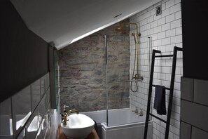 Een bad/douchecombinatie, een haardroger, handdoeken