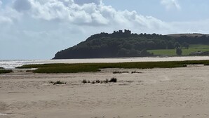 A beach with a distant hill and castle.