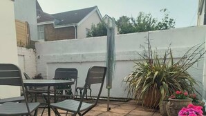 An outdoor patio with stone flooring, a table with chairs, and potted plants. - Stunning 1-Bed Apartment in Southsea (Southsea)
