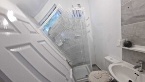 A bathroom with a shower enclosure, toilet, sink, and a small decorative item on the sink.