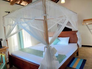 A bed with a wooden headboard, white bedding, and a mosquito net. - Villa by Tamarind Shade (Talalla)