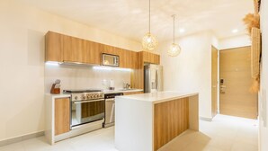 A modern kitchen with wooden cabinets, stainless steel appliances, and pendant lighting. - Santamar by TAO (Akumal)