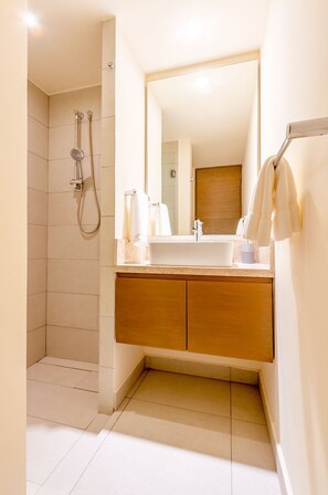 A modern bathroom with a walk-in shower, a large mirror, and a wooden vanity. - Santamar by TAO (Akumal)
