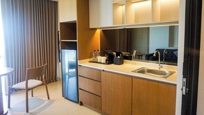 A modern kitchen with wooden cabinets, a built-in sink, and a coffee maker. - Nusa Dua Suites Bali powered by Cocotel (Nusa Dua)