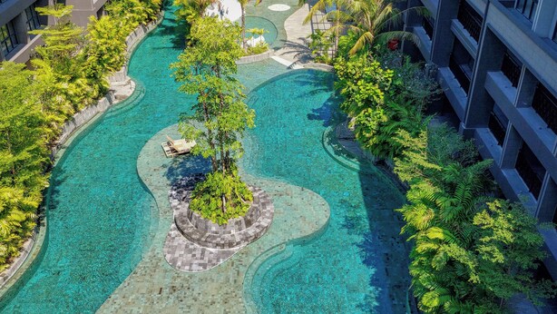 A resort with a large, clear swimming pool surrounded by lush greenery and modern buildings. - Nusa Dua Suites Bali powered by Cocotel (Nusa Dua)