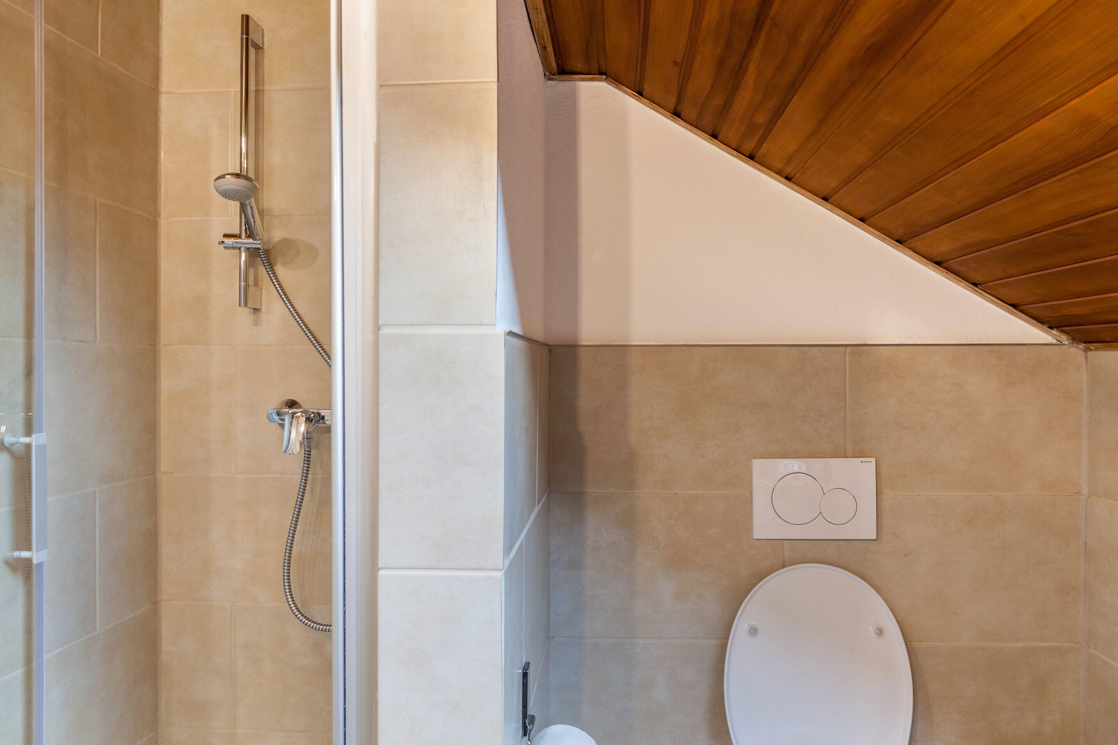 A bathroom with a shower, toilet, and a control panel on the wall.