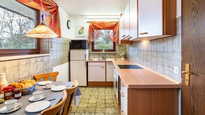 Une cuisine compacte comprenant un coin repas, un réfrigérateur, un évier et une fenêtre avec des rideaux.
