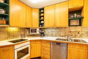 Une cuisine équipée de meubles en bois, d’un four à micro-ondes, d’une machine à café, d’un lave-vaisselle et d’une cuisinière.