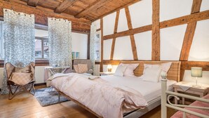 A bedroom with a large bed, two bedside tables, a chair, and a window with curtains. - Apartment 'Lemkamp Klein' with Wi-Fi (Markdorf)