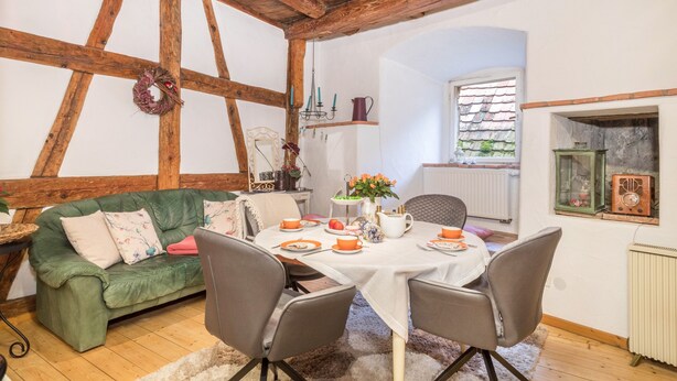 A cozy dining area with a wooden ceiling, a green sofa, and a table set for two. - Apartment 'Lemkamp Klein' with Wi-Fi (Markdorf)