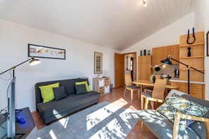 A modern living room with a sofa, a dining table, and a kitchen area. - Holiday Apartment "Naturnahe" with Private Terrace, Shared Garden & Wi-Fi (Deuerling)