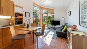 Een moderne keuken met houten kastjes, een eethoek met een tafel en stoelen, een bank en een televisie.