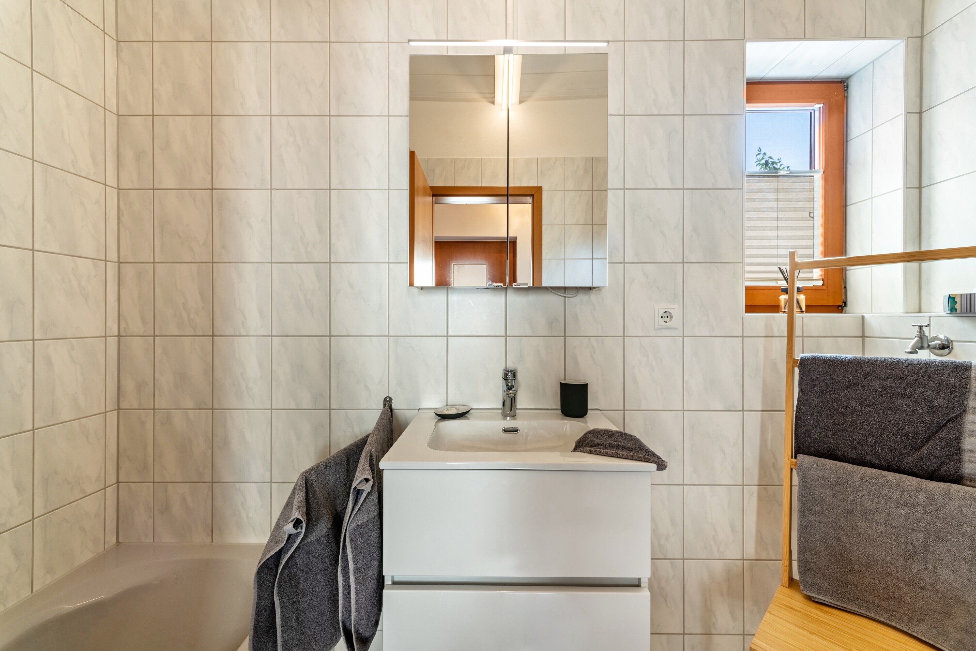 Un baño con lavamanos, espejo y perchero para toallas.