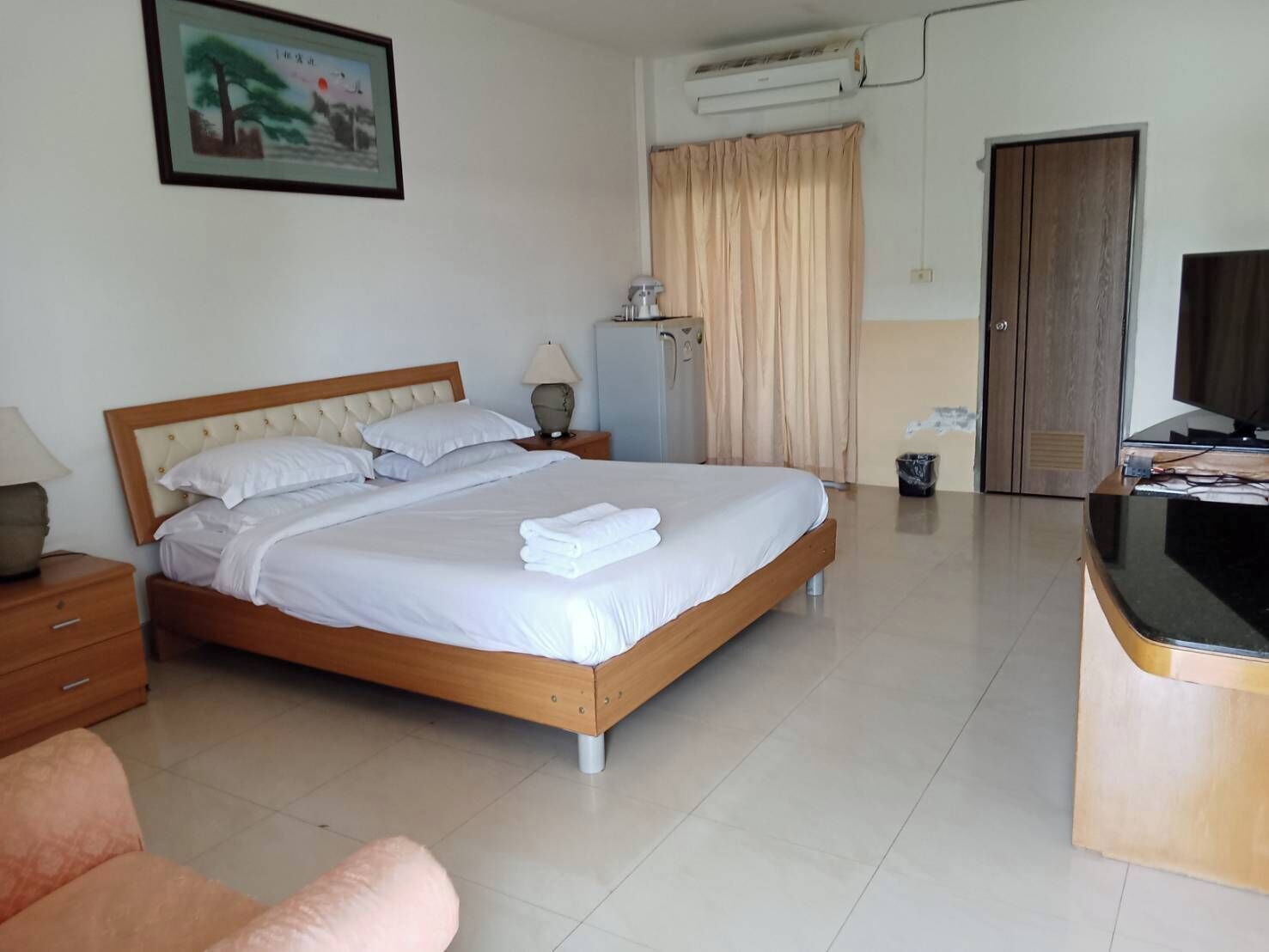 Habitación de hotel con cama, escritorio, silla, televisor y baño.
