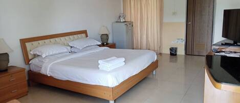 Habitación de hotel con cama, escritorio, silla, televisor y baño.