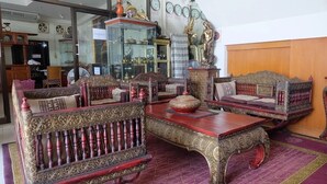 A traditional room with ornate furniture, including a sofa and a table with intricate designs. - Thai Ngam Palace Hotel (Kaeng Khlo)