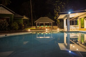 Piscina com área de estar coberta e espreguiçadeiras.