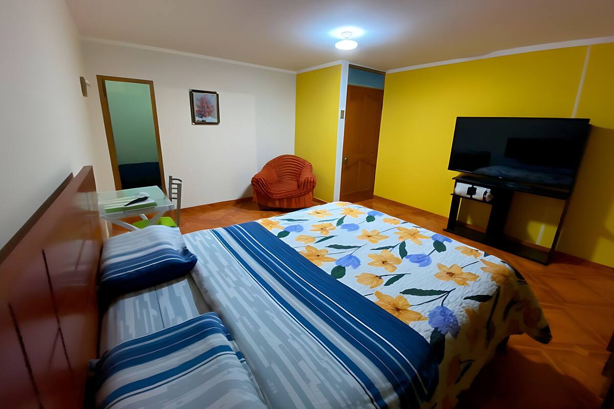 Una habitación con dos camas, una silla, un escritorio, un televisor y una puerta.