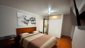 Un dormitorio moderno con cama, mesitas de noche, un espejo y una lámpara de techo.