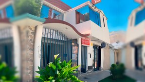 Un edificio moderno de dos pisos con fachada de piedra, un gran ventanal y un letrero rojo que indica un negocio.