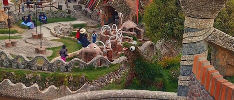 A hotel with a unique architectural design, featuring a prominent tower and a landscaped garden.