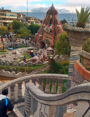 A hotel with a unique architectural design, featuring a prominent tower and a landscaped garden. - Sta. Lucia 223 (Huancayo)