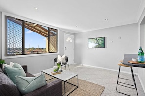 Relax in this cozy living space with a comfortable sofa, mounted TV, and scenic view.