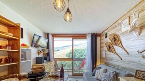 Una sala de estar acogedora con una mesa de comedor de madera, un sofá y un televisor instalado en la pared.