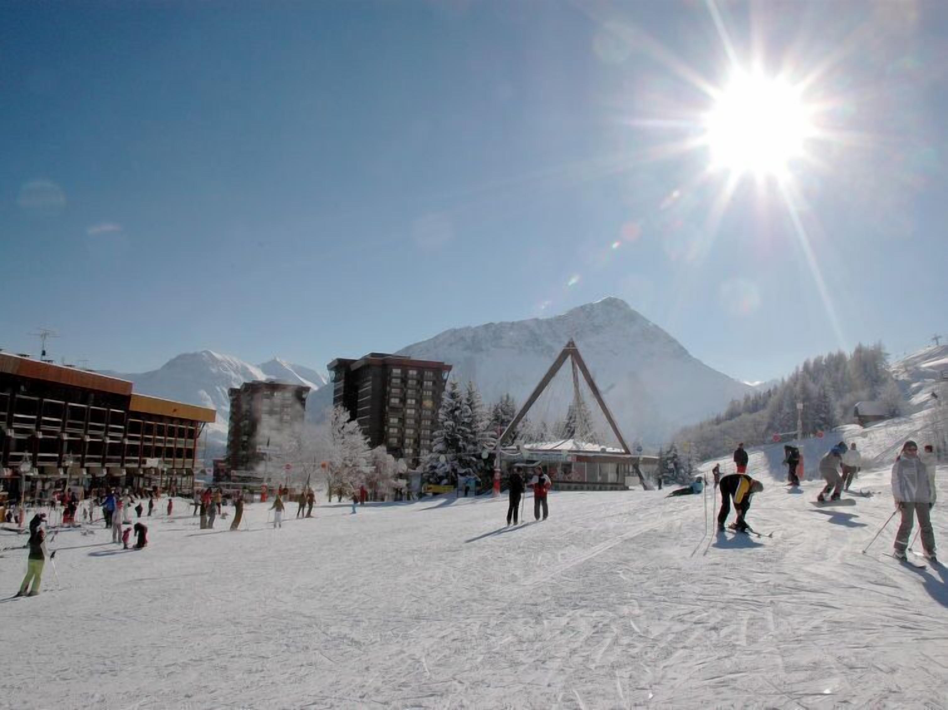 A ski resort with a large building, a ski lift, and a mountain in the background.
