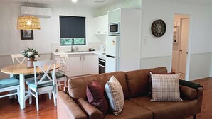 Una cocina moderna con armarios blancos, microondas y cafetera.