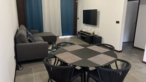 Una sala de estar con sofá, televisión y comedor con mesa y sillas.